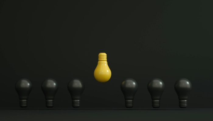 A single yellow light bulb highlighted among dark ones symbolizing creativity and innovation.